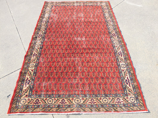 Close-up detail of distressed Persian pattern on hand-knotted vintage wool rug.